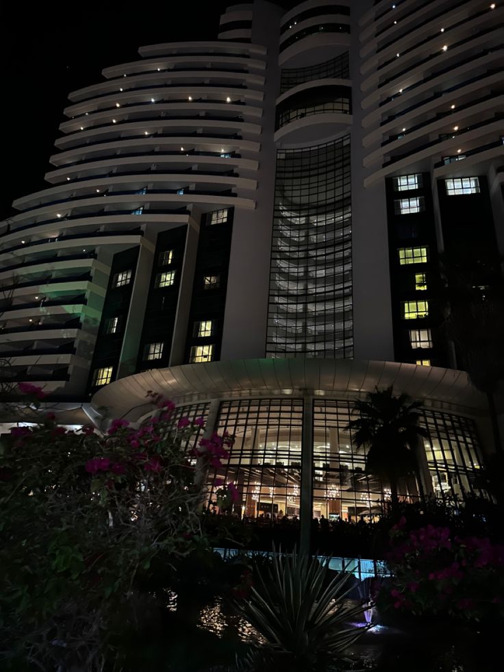 a very tall building with lots of windows and lights on it's sides at night