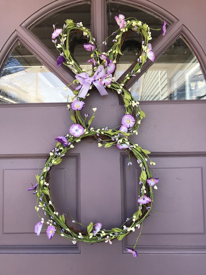 a wreath with purple flowers hanging on the front door