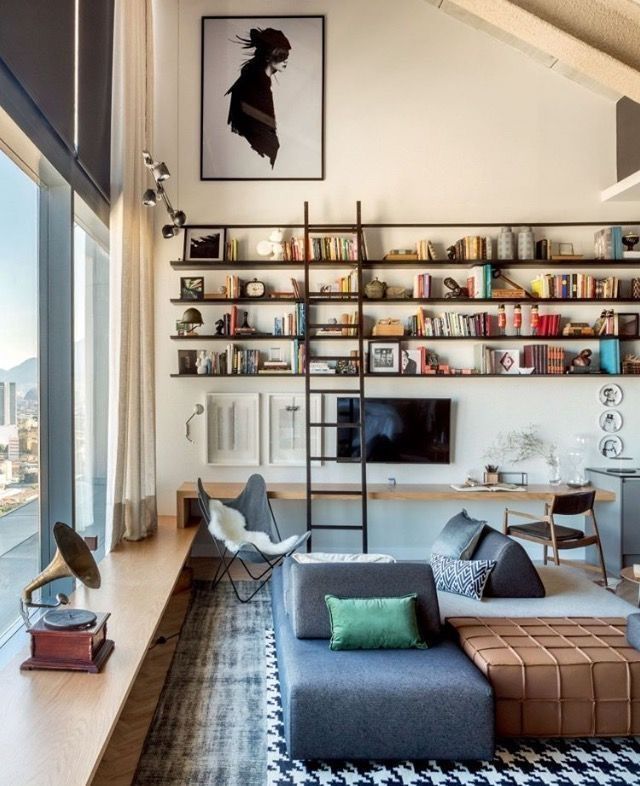 a living room filled with lots of furniture and bookshelves next to a window