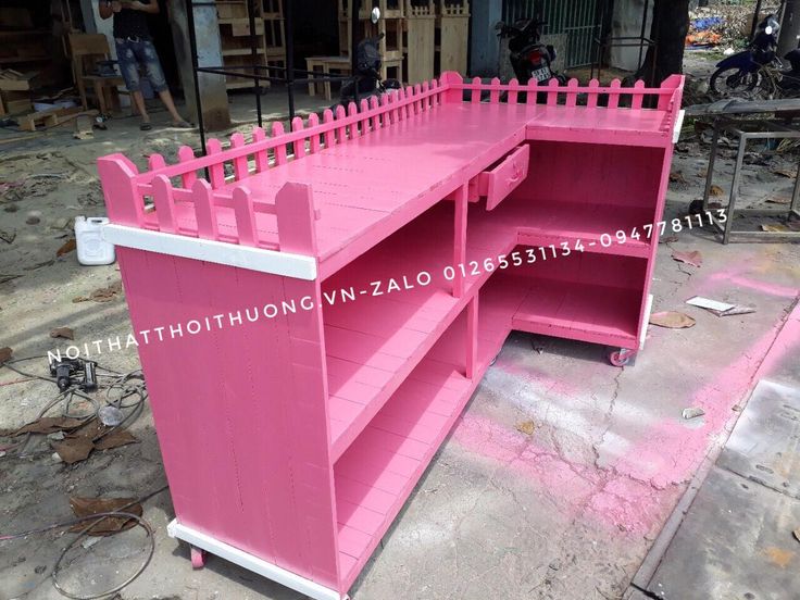 a pink wooden desk sitting on top of a sidewalk