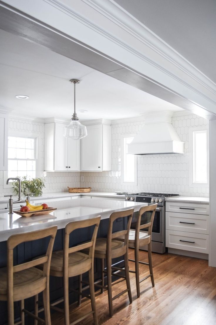 a kitchen with white cabinets and an island in the middle, surrounded by bar stools