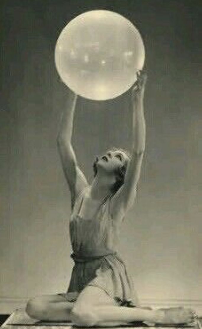 a woman is sitting on the floor holding a large bubble in her hand and looking up into the sky