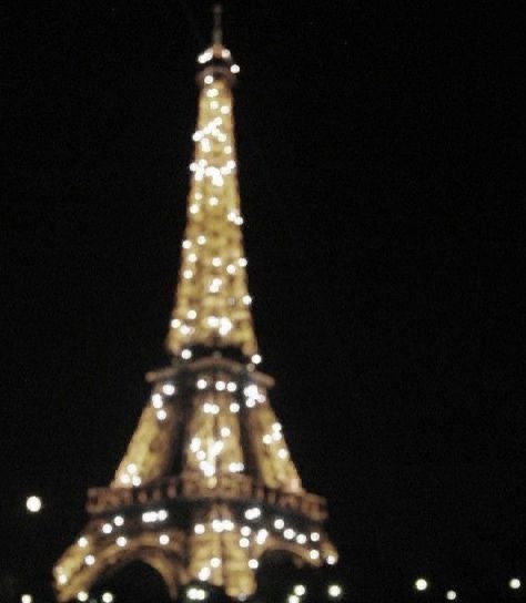 the eiffel tower lit up at night with lights on it's sides