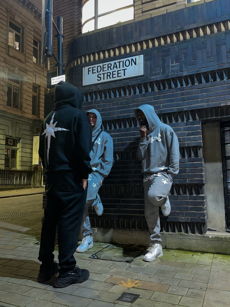 two men in hoodies standing next to a brick building with a sign that says federal street