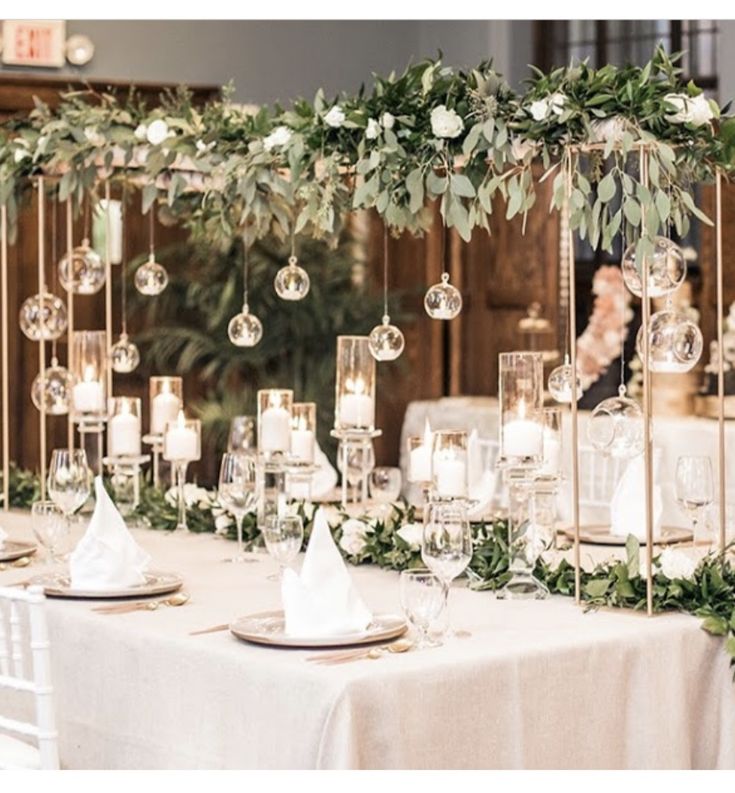 the table is set with candles, greenery and glassware for an elegant wedding reception