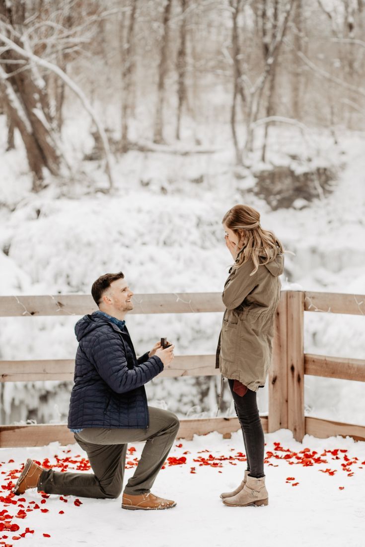 a man kneeling down next to a woman in front of a fence with rose petals on it