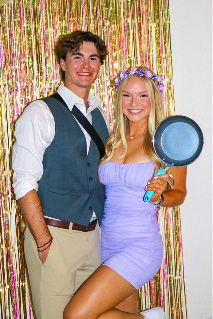 a man and woman pose for a photo in front of a backdrop with streamers