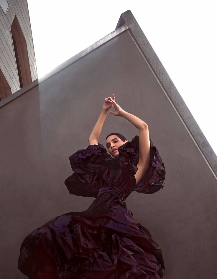 a woman in a long purple dress is posing for the camera with her hands up