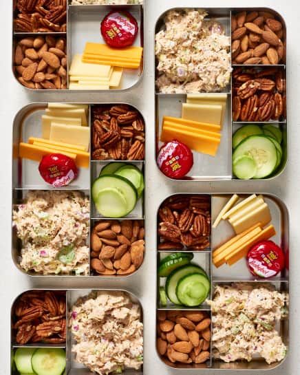 four trays filled with different types of food and nuts on top of each other