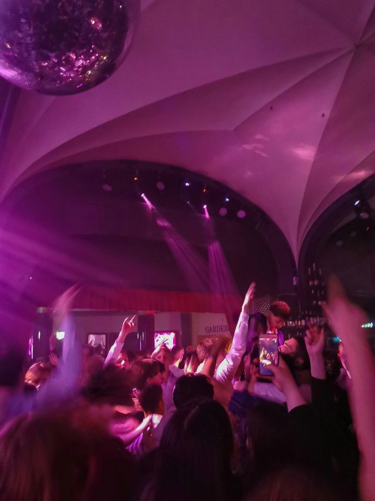 a group of people are dancing at a party with their hands up in the air