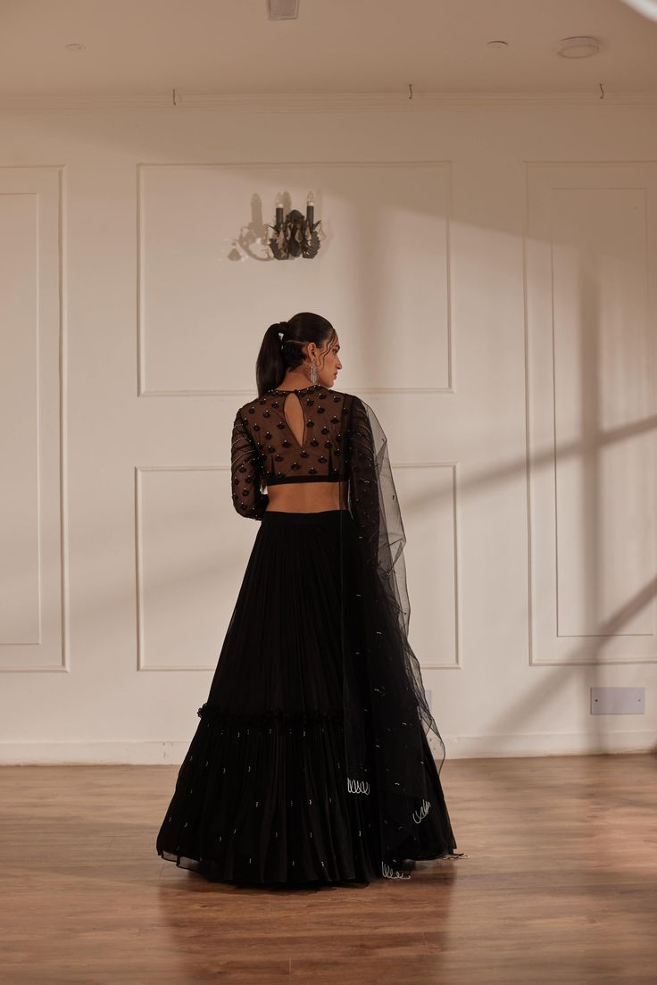 Black fully embroidered choli with net sleeves paired up with georgette layered lehenga and black net dupatta. No. of pieces in a set: 3 Color: Black Fabric Composition: Net,georgette, opada silk Lining Material: Shantoon Closure used: Side zip in both choli and lehenga Dress Length : Full Silhouette: Gathered Neck type : Round neckline Sleeve Length: full Sleeves Waistline: High waist Prints/ Pattterns : Plain Delivery Time: 20-25 days Elegant Black Organza Choli, Black Organza Choli For Festive Occasions, Black Organza Sharara For Reception, Black Organza Pre-draped Saree With Sheer Dupatta, Fitted Black Anarkali Pre-draped Saree, Evening Organza Lehenga With Cutdana, Black Organza Blouse Piece With Dupatta, Black Organza Floor-length Lehenga, Black Floor-length Organza Lehenga