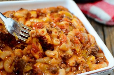 a fork is in a casserole dish with meat and cheese on it, ready to be eaten