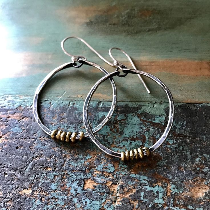 "These thick hammered hoops are a great every day size. Made of 14 gauge sterling wire that I've forged, oxidized and polished to a matte finish. I've added some tiny brass Ethiopian heishi beads for a mixed metal contrast. They hang from sterling earwires. 1 1/2\" diameter (2nd photo, small pair)" Artisan Small Hoop Earrings With Oxidized Finish, Small Metal Hoop Earrings With Soldered Detail, Artisan Hoop Earrings With Oxidized Finish, Artisan Oxidized Hoop Earrings, Small Hoop Metal Earrings With Soldered Details, Everyday Metal Hoop Earrings With Oxidized Finish, Artisan Oxidized Finish Earrings For Everyday, Artisan Hand Forged Hoop Earrings, Gift Circle Hoop Earrings With Oxidized Finish