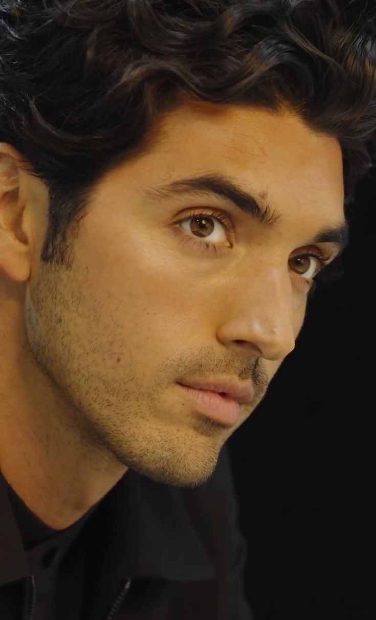 a close up of a person wearing a black shirt and looking at the camera with a serious look on his face