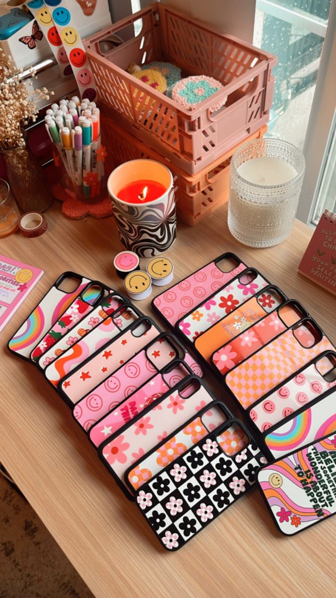 Desk with a candle lit and markers. Phone cases laid out on desk. Happy face phone grips. Checker patterns, flowers, happy faces, quotes, hand lettering, rainbows, strawberries, stars Cricut Phone Case Ideas, Girl Boss Print, Rome Flynn, Cute Ipod Cases, Phone Cases Ideas, Trendy Iphone Cases, Boutique Gifts, Trendy Phone Cases, Ipod Cases