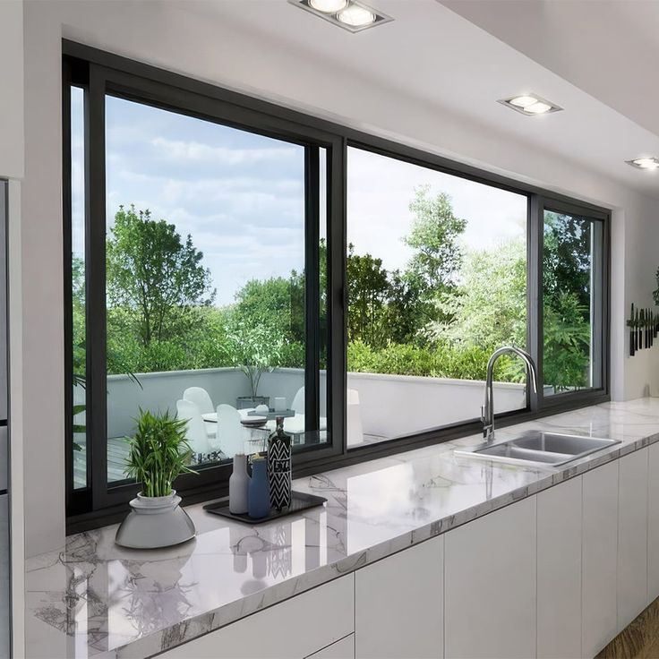 a kitchen with marble counter tops and large windows looking out onto the trees in the distance