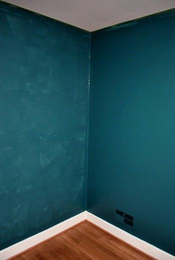 an empty room with blue walls and wood flooring in the corner is painted teal