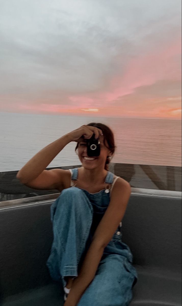 a woman sitting in the back of a truck looking through a binoculars lens at the ocean