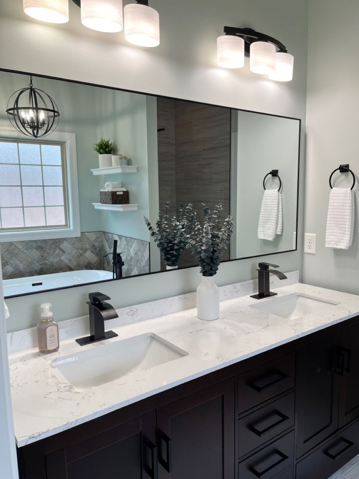 a bathroom with double sinks and large mirrors