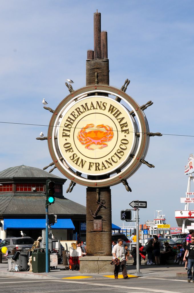 the sign for fisherman's wharf in san francisco is lit up and people are walking around