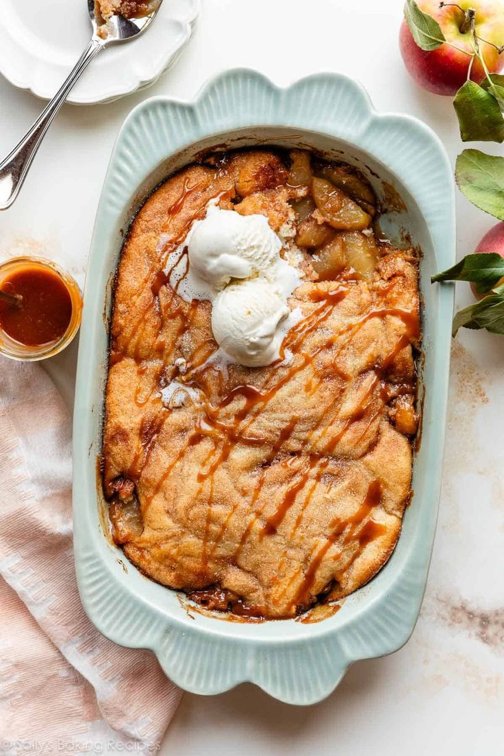 an apple cobbler with ice cream on top in a blue dish next to apples