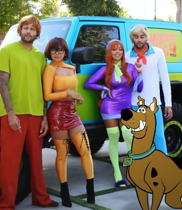 some people are standing in front of a blue truck with the scooby gang on it