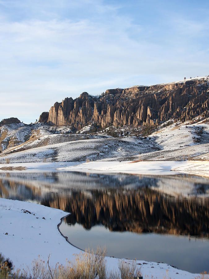 the mountains are covered in snow near a lake