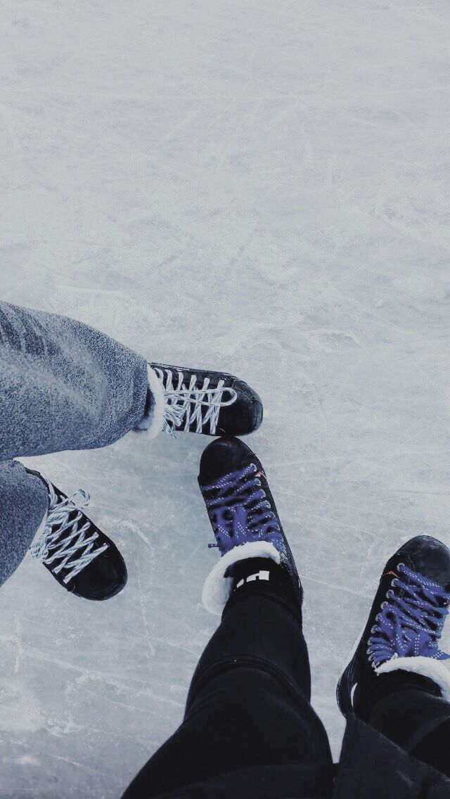 two people standing in the snow with their feet on each other's legs, one wearing blue and white sneakers