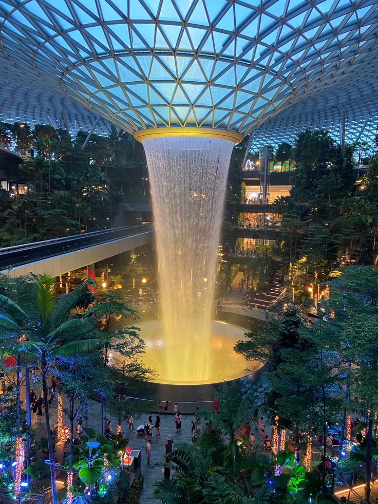 the inside of a building with a fountain in the center and people walking around it