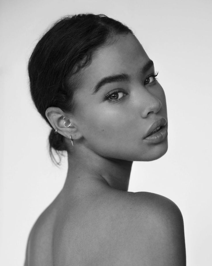 a black and white photo of a woman with earrings on her head looking off to the side