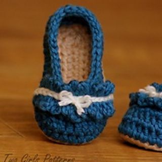 two crocheted blue baby shoes sitting on top of a wooden table next to each other