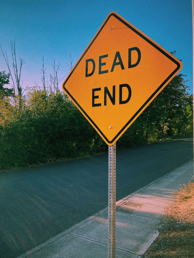 a yellow dead end sign sitting on the side of a road