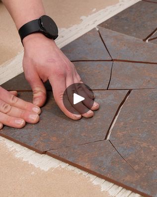 a person is laying out some tiles on the floor with their hands and thumbnails