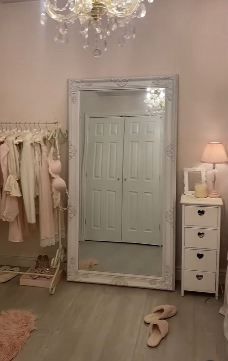 a bedroom with a chandelier, mirror and shoes on the floor