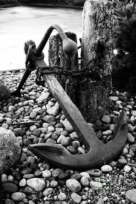 black and white photograph of an anchor on rocks