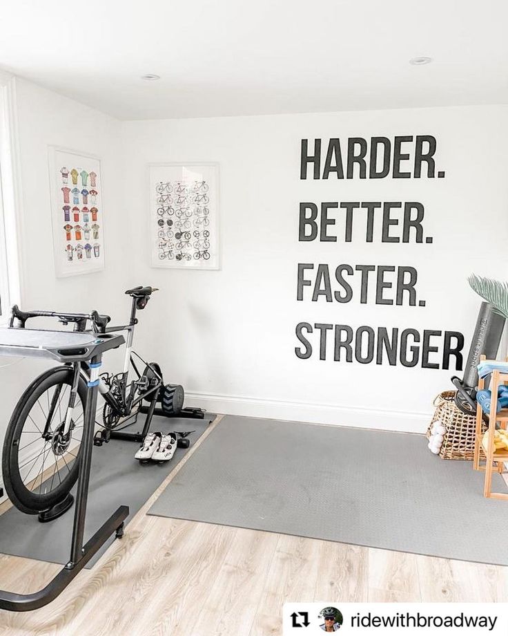 there is a bike and exercise equipment in this home gym area with the words harder, better, faster, stronger written on the wall