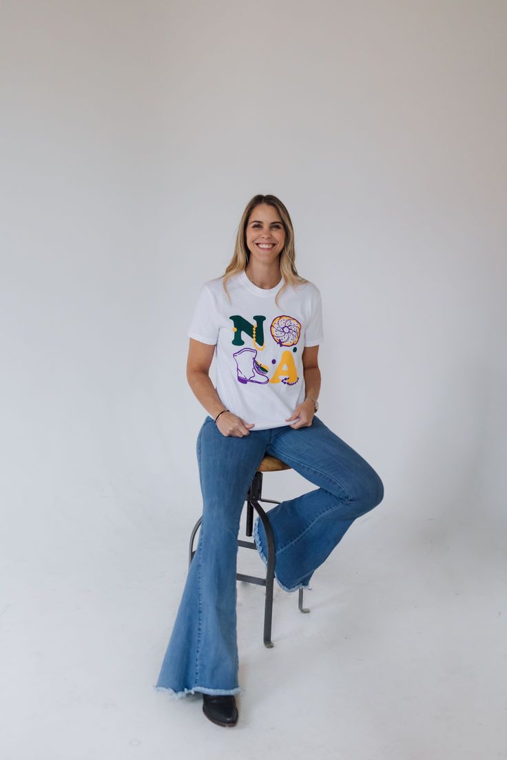 a woman sitting on top of a stool wearing flare jeans and a t - shirt