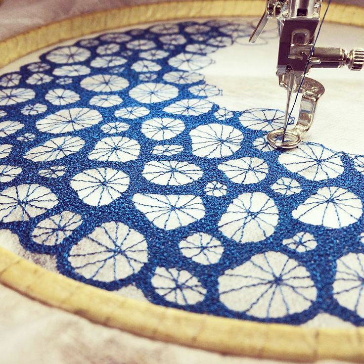 an embroidery machine is working on a blue and white circular piece of fabric that has been sewn