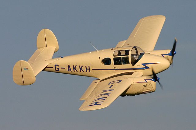 a small white airplane flying through a blue sky