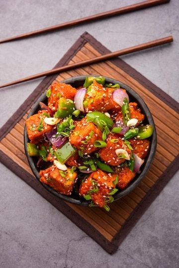 a bowl filled with meat and veggies next to chopsticks on top of a table