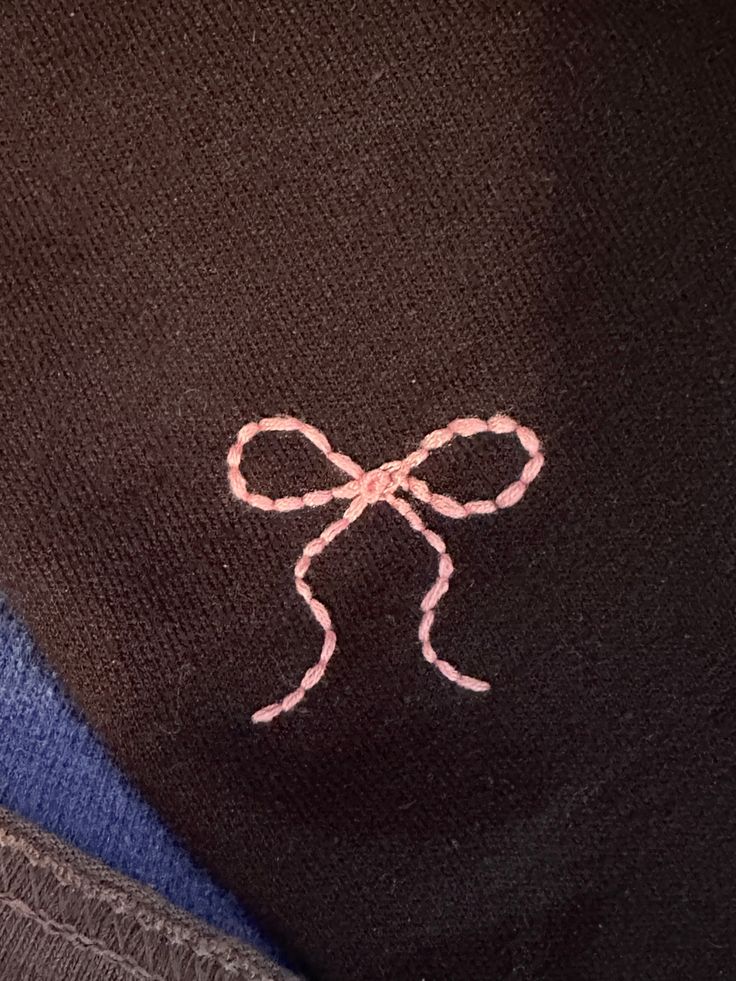 an embroidered bow on the back of a black shirt with blue and gray shirts underneath it