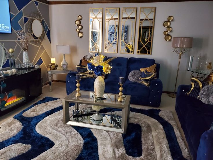 a living room filled with blue couches and gold mirrors on the wall above them