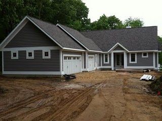 a house that is being built in the middle of some dirt and grass with two garages on each side