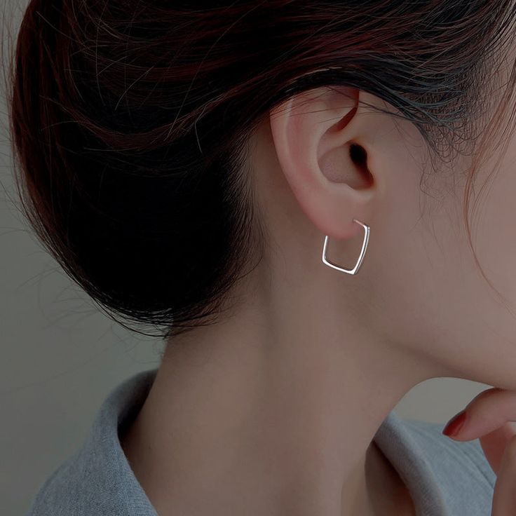 a woman wearing a pair of silver hoop earrings on her left ear and the other half of her right ear