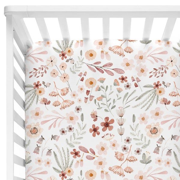 a white crib with pink and orange flowers on it