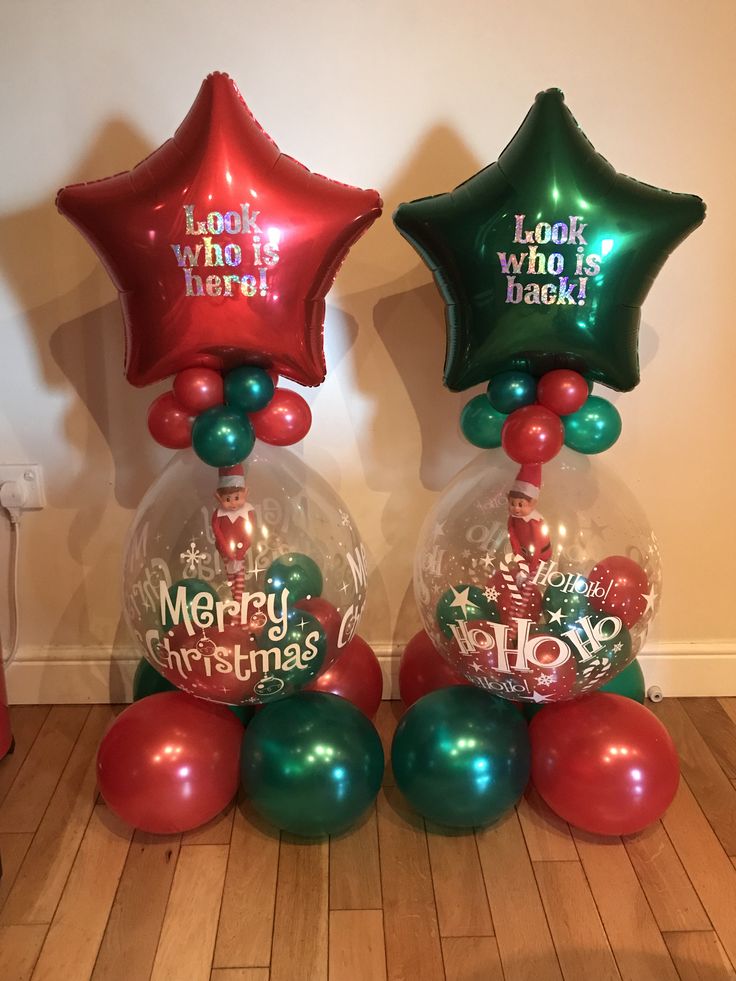 three star shaped balloons in the shape of christmas balls with merry lettering on them, sitting on a wooden floor