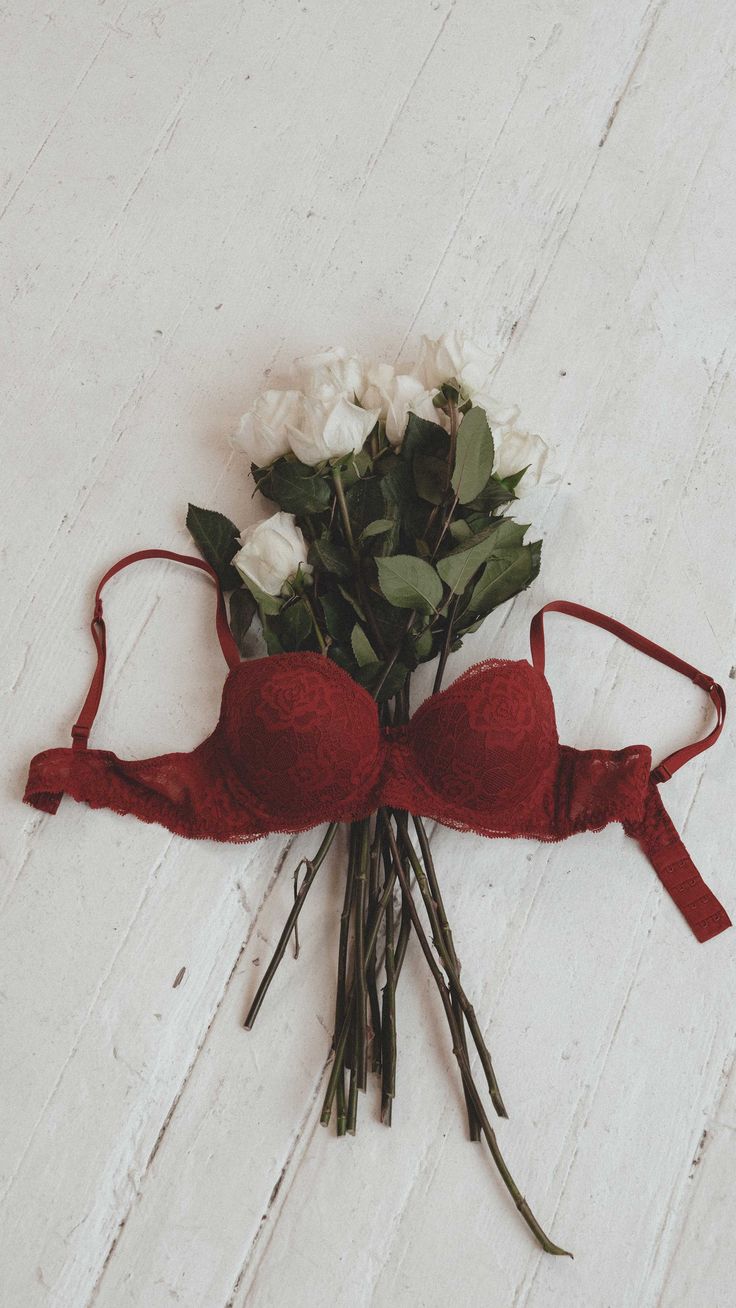 a bouquet of flowers tied to a red ribbon on a white wooden background with space for text