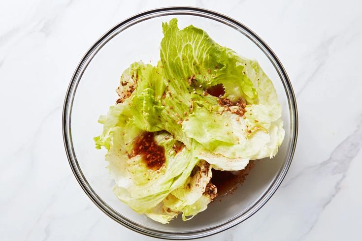 a glass bowl filled with lettuce on top of a white counter