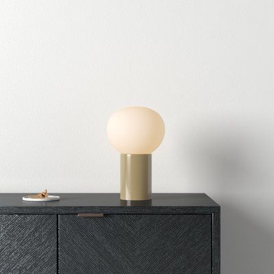 a table lamp sitting on top of a black cabinet next to a white wall and floor