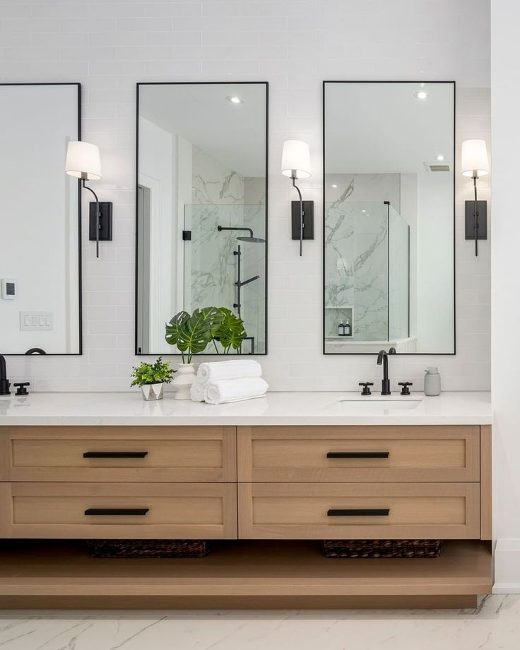 a bathroom with two sinks and three mirrors